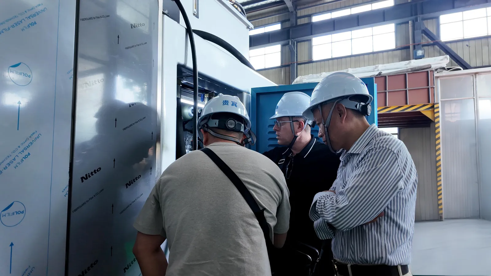Kyrgyz visitors looking at a leather machine under assembly at SREE